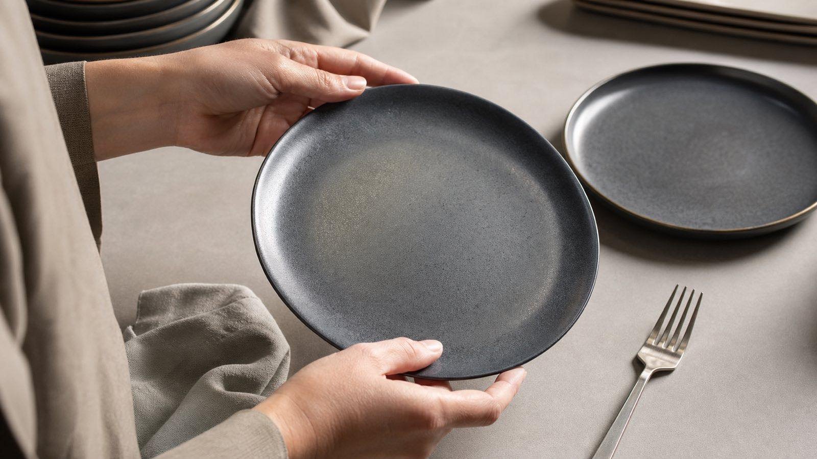 buyer checking ceramic plate glaze under angled light after utensil testing